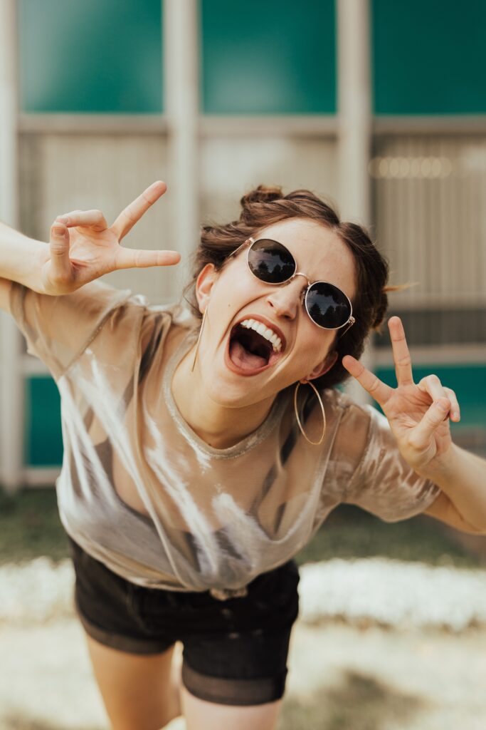 happy girl is doing the peace sign and laughing at the camera