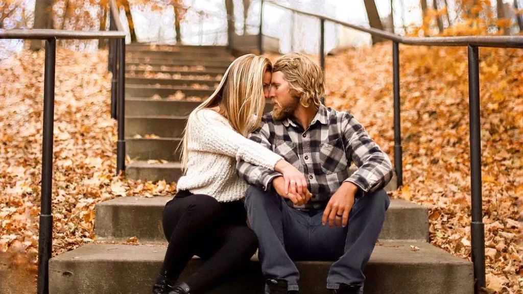wholesome couple sitting on a staircase in an autumn setting, kissing romantically