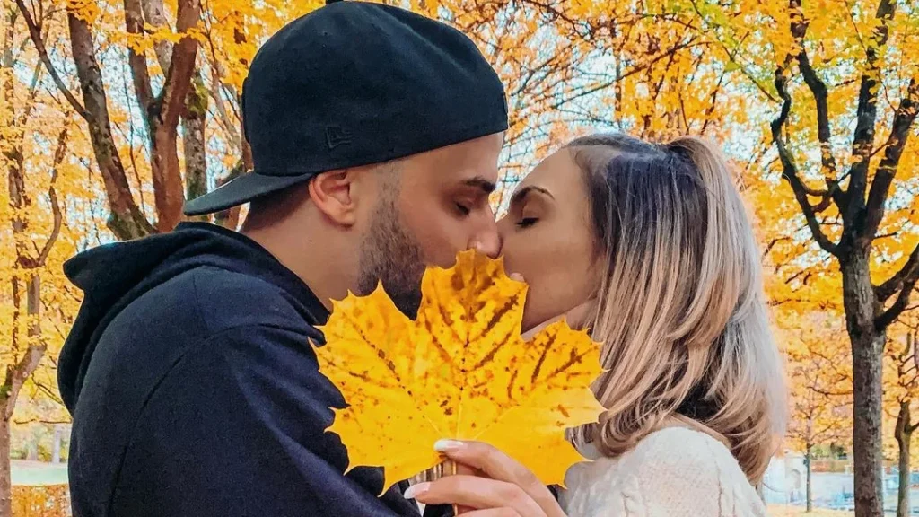 kissing couple holding a fall leaf in front of their faces to hide their kiss, marble leaf