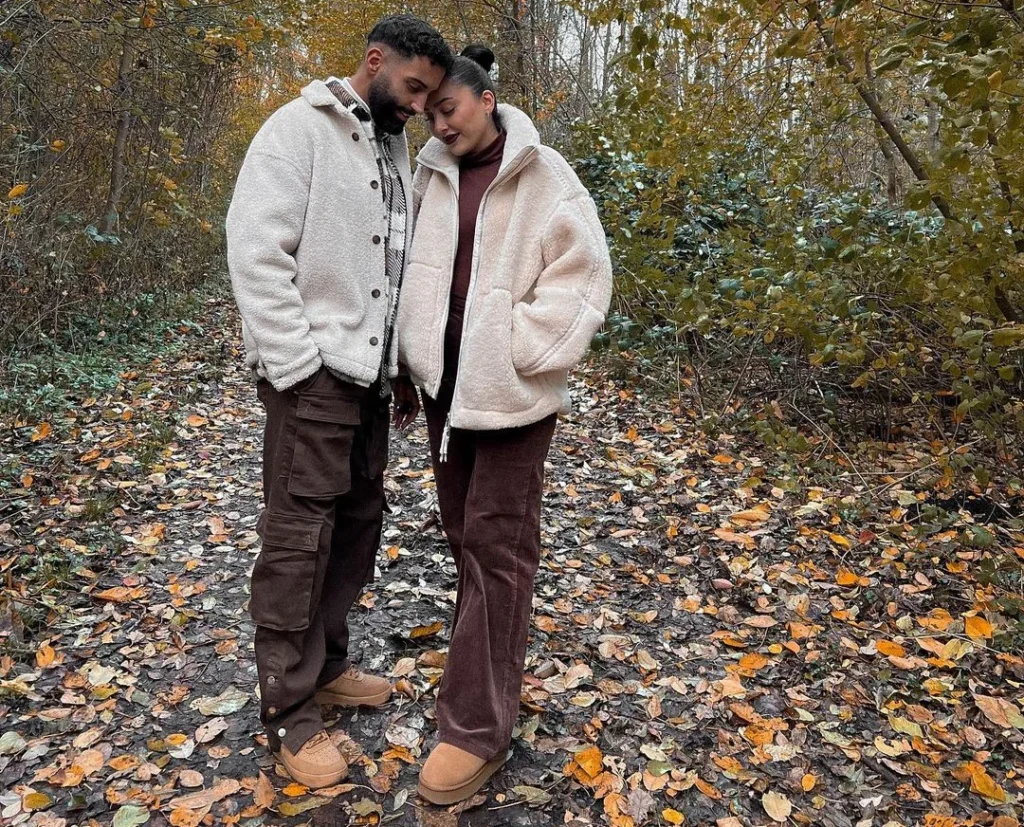 cute couple holding their heads together wearing completely matching couple outfit for a photoshoot in the forsest