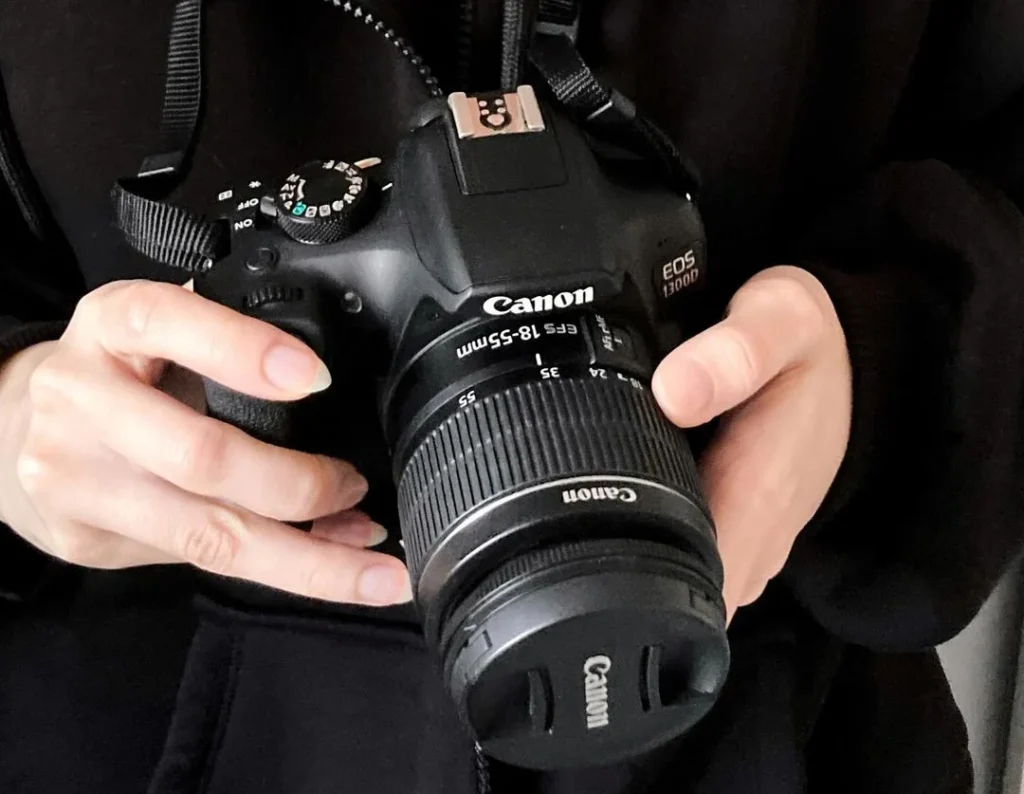 beginner photographer girl holding her canon eos t300D camera to begin shooting her first photos on the best canon camera for beginners