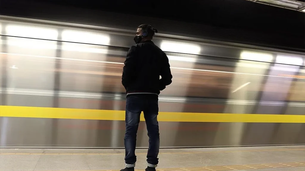 man posing in front of a train passing by to get a cool motion blur effect due to long exposure portrait photography